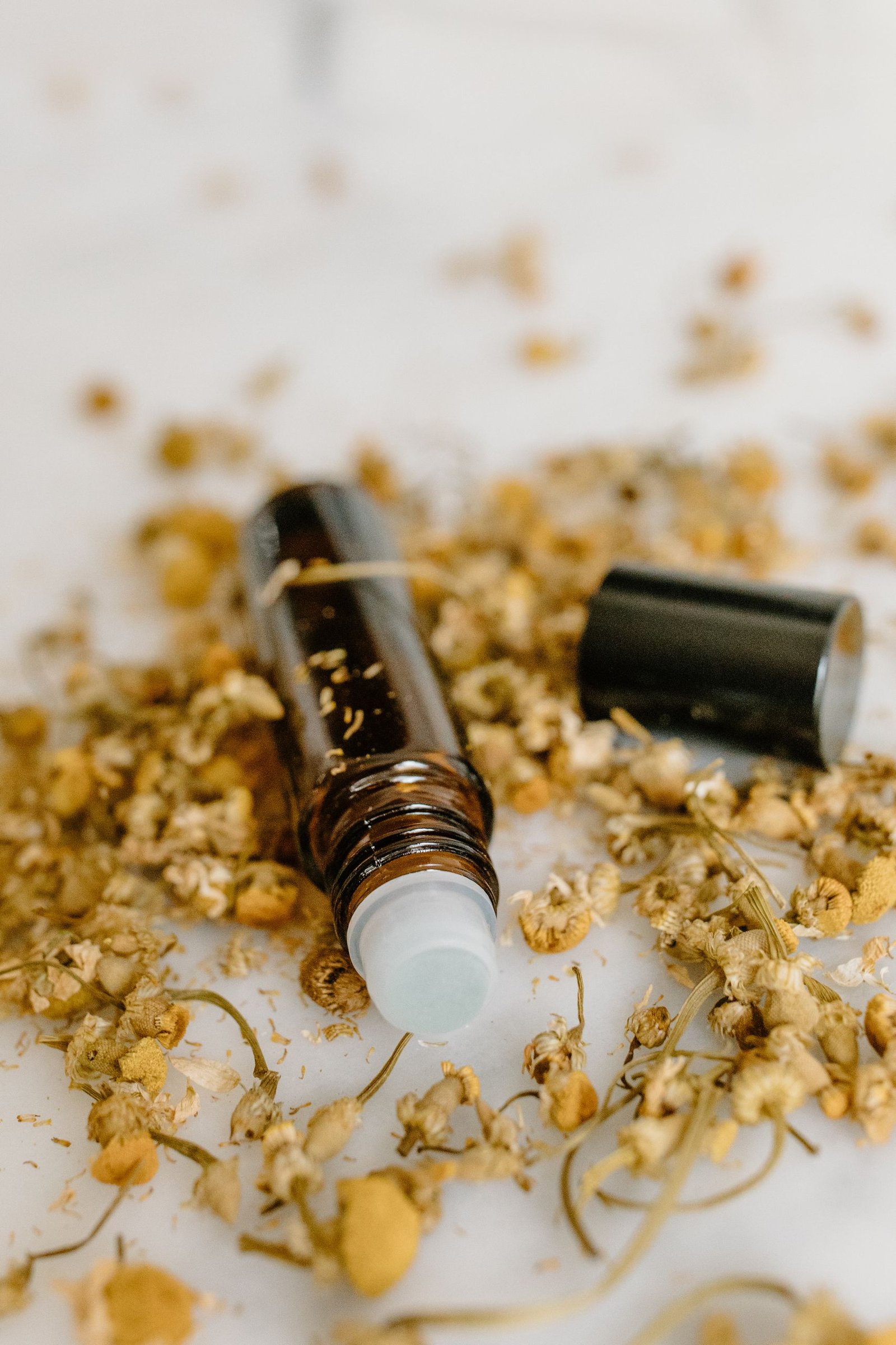 Aromatic rollers alongside dried chamomile flowers, perfect for natural and holistic concepts.
